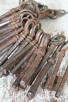 an old bunch of rusty keys sitting on top of a white cloth covered tablecloth