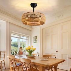 a woman sitting at a table in a room with chairs and a chandelier