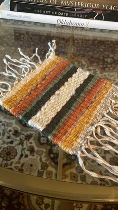 a close up of a knitted scarf on a table with books in the background