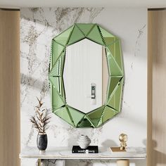 a green mirror sitting on top of a white table next to a vase filled with flowers