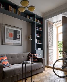 a living room filled with furniture and a bike parked in front of a bookshelf