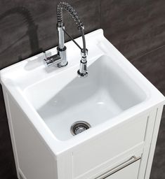 a white sink sitting under a faucet next to a wall mounted faucet