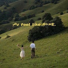 a man and woman standing on top of a lush green hillside