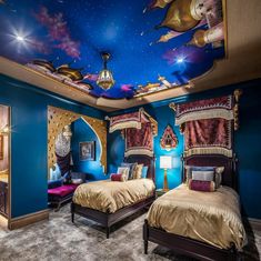 two beds in a room with blue walls and paintings on the ceiling, one is gold and the other is red