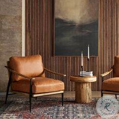 two brown chairs sitting next to each other in front of a painting on the wall