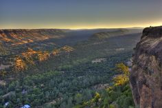 the sun is setting over some mountains and trees