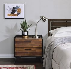 a bedroom with a bed, nightstand and plant on the side table next to it