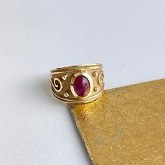 Estate/ vintage 14KT yellow Gold Byzantine/ Etruscan design polished + textured matte finish cigar band ring with genuine ruby. Elegant, old world piece with faceted, oval-shaped, cabochon, genuine red ruby. Ruby measures: 8mm x 5.7mm Size 7 Can be sized by your local jeweler or ours for a fee Solid Measures: 13.6mm wide~ graduated back to 3.5mm Weight: 4.6 grams Excellent condition Classic Oval Engraved Ruby Ring, Luxury Engraved Oval Ruby Ring, Byzantine Oval Gemstone Jewelry, Byzantine Style Oval Gemstone Jewelry, Byzantine Oval Gemstone Ring, Oval Byzantine Gemstone Ring, Elegant Hand Forged Yellow Gold Ruby Ring, Antique Oval Ruby Ring, Oval Ruby Ring Engraved