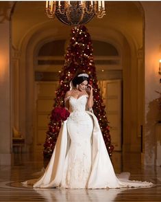 a woman in a wedding dress standing next to a christmas tree talking on her cell phone