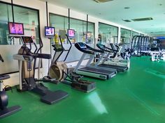 there are many treadmills in the gym with mirrors on the wall behind them