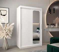 a room with a bed, mirror and green chair in front of the door that is open