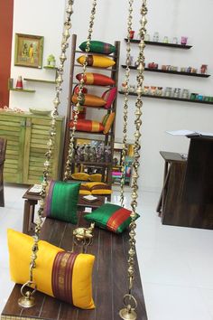 a living room filled with lots of different colored pillows and chains hanging from the ceiling