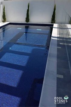 an empty swimming pool with blue tiles on the floor and side walk leading up to it