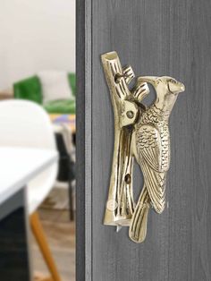 a door handle with a bird on it and a white table in the back ground