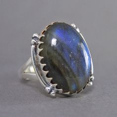 SKU: SS-015Material: 925 stamped sterling silverGemstone(s): Labradorite (N)Gemstone Dimensions: 15 X 23 X 4 mmRing Size: US 7Weight: 9.3 gramsThis unconventional Labradorite cabochon ring features a large oval Labradorite in a Jagtooth bezel, accented with curved lines at the sides. The Labradorite glows with a medium deep blue fire, as if there is a light emanating from the stone. There are also hints of mica within the stone, which add a touch of glitter. There Is A Light, Cabochon Ring, Blue Fire, Rings Statement, Deep Blue, Sterling Silver Ring, Labradorite, The Stone, Statement Rings