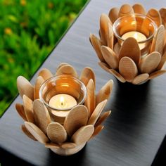 two wooden lotus candle holders sitting on top of a black table next to each other