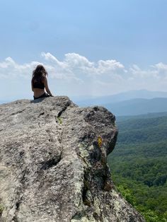 a woman sitting on top of a large rock