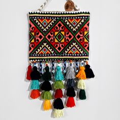 an embroidered wall hanging with tassels and beads on it's side,