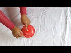 a person holding a red object on top of a white sheet covered table with circles