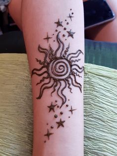 a woman's arm with a sun and stars tattoo design on the side of it