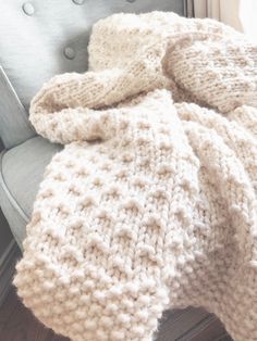 a white blanket sitting on top of a chair next to a window