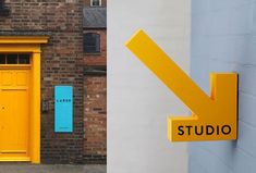 two yellow doors and one blue door in front of a brick building with the word studio painted on it