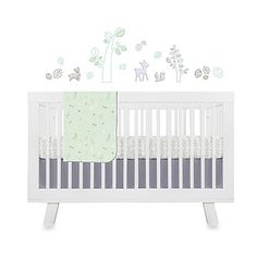 a white crib with green and gray wall decals