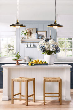 two stools in front of a kitchen island with flowers and lemons on it