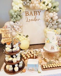 a table topped with lots of cakes and cupcakes next to a sign that says baby leader