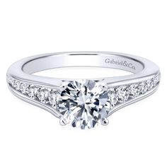 a white gold engagement ring with channel set diamonds on the sides and side stones around the band