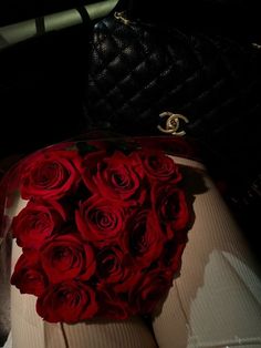 a bouquet of red roses sitting in the back seat of a car next to a purse