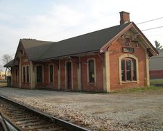 an old red brick train station sitting next to a railroad track with no cars on it