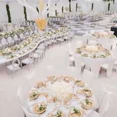 a banquet hall with tables and chairs set up for formal dinnereons, decorated with white flowers and greenery