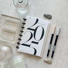 an open notebook sitting on top of a table next to some pens and other items