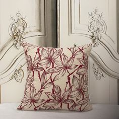 a red and white pillow sitting on top of a bed next to an ornate headboard