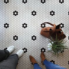 a woman's feet and purse on a tiled floor with black and white tiles