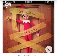 an elf is holding up some yellow paper taped to the door and it says don't play with tape