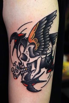 a tattoo with a skull and wings on the arm