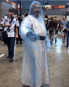 a man dressed as jesus is standing in the middle of an indoor area with people walking around