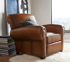 a brown leather chair sitting in front of a window