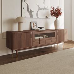 a living room with a large painting on the wall next to a wooden entertainment center