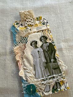 an altered photo is displayed on a piece of fabric with buttons and lace around it