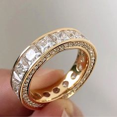 someone is holding a gold ring with white stones on it and there are two rows of diamonds in the middle