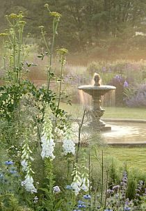 there is a fountain in the middle of some flowers