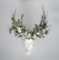 the antlers are adorned with white flowers and greenery