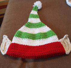 a crocheted christmas hat sitting on top of a brown couch next to other items