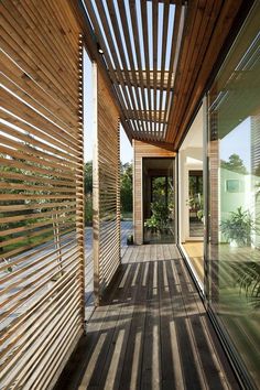 a wooden walkway leading to a building with glass walls and wood slats on the sides