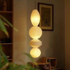 three paper lanterns hanging from the ceiling in a living room with chairs and bookshelves