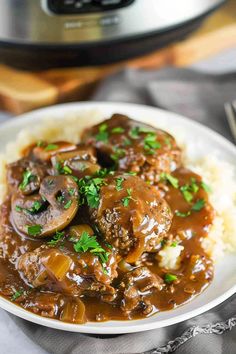 a white plate topped with meat and gravy covered in gravy next to an instant pressure cooker