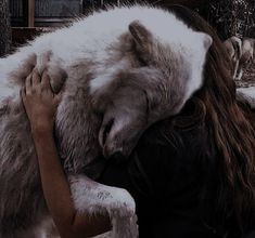 a woman is hugging a large white bear in her arms and it's face to the side